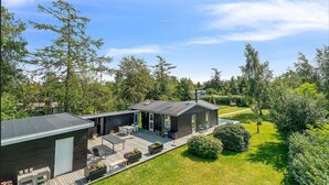 Ein modernes Haus mit Terrasse, Rasen und Blick zum Himmel.