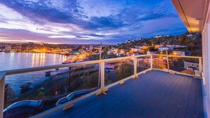 Un balcon offrant une vue sur le paysage urbain au bord de l’eau, au crépuscule.