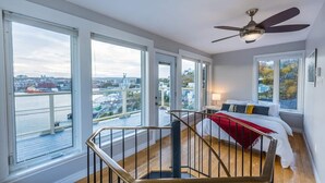 Une chambre avec un lit, une vue sur la ville et un balcon doté d’une balustrade.