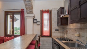Una cocina con encimera de piedra, sillas de madera, estufa y pileta.