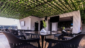 Een dakterras met zwarte stoelen en een tafel, omgeven door groen en een modern design.