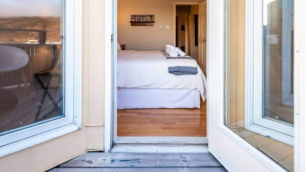 Una camera da letto con un letto, un tavolino, una sedia e un balcone con vista.