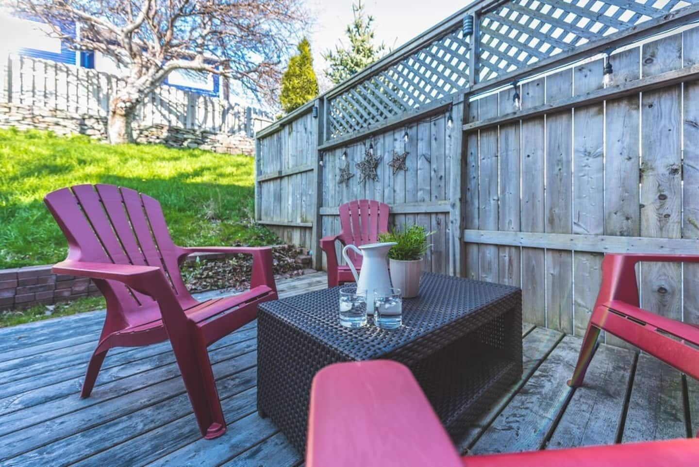 Een terras met twee Adirondack-stoelen, een kleine tafel en een bloempot.