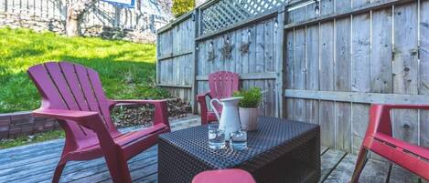 Een terras met twee Adirondack-stoelen, een kleine tafel en een bloempot.