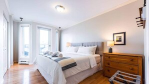 Un'ampia camera da letto con un letto grande, una cassettiera in legno e una finestra con vista.