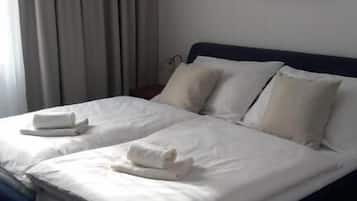 A neatly made double bed with white linens, a dark headboard, and a framed picture on the wall.