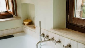 A modern bathroom with a freestanding bathtub, a window, and a shelf with a towel. - La Casa Delle Api  (Offida)