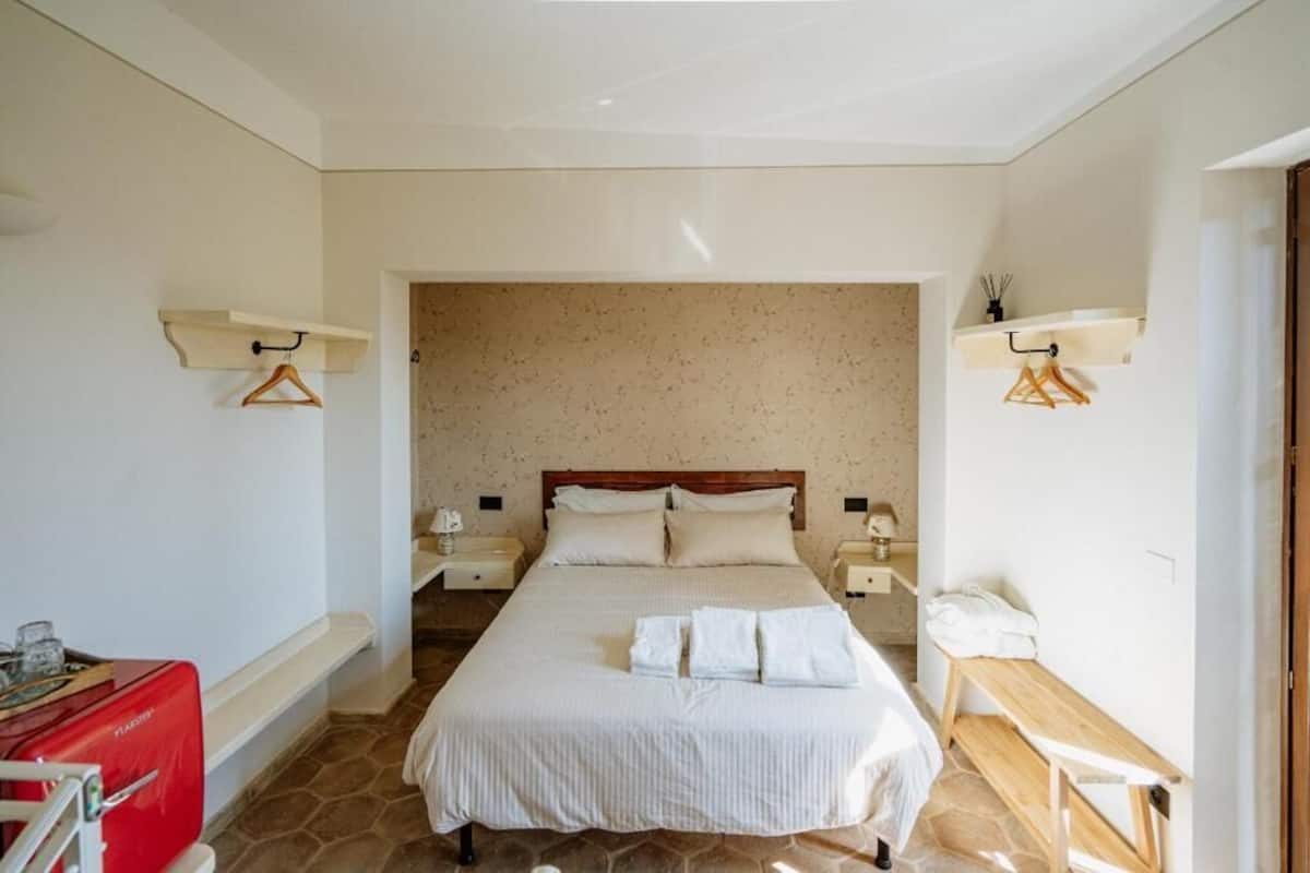 A neatly arranged bedroom with a large bed, bedside tables, and a bench.