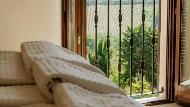 A room with a bed, a window with a view of a green landscape, and a balcony with a metal railing. - La Casa Delle Api  (Offida)
