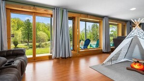 Un salón amplio con un gran ventanal corredera que da a un jardín.