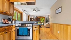 Una cocina con armarios de madera, estufa de acero inoxidable y ventilador de techo.
