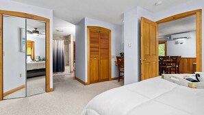 Un dormitorio con una cama grande, un armario de madera, un espejo y un ventilador de techo.