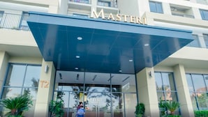 The entrance of a hotel named "MASTER1" with a modern glass facade and a blue awning. - Masteri Thao Dien Apartment  Quan 2 (Ho Chi Minh City)