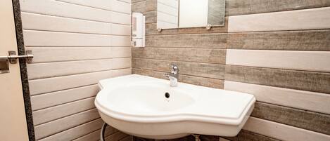Un baño con un lavabo blanco, un espejo y un dispensador de toallas.