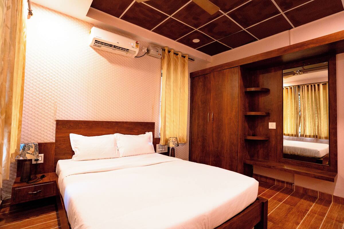 A hotel room with a large bed, wooden headboard, and a built-in wardrobe.