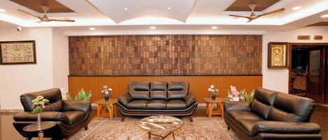 Una sala de estar moderna con un sofá de cuero marrón, una mesa redonda de centro y una alfombra estampada.