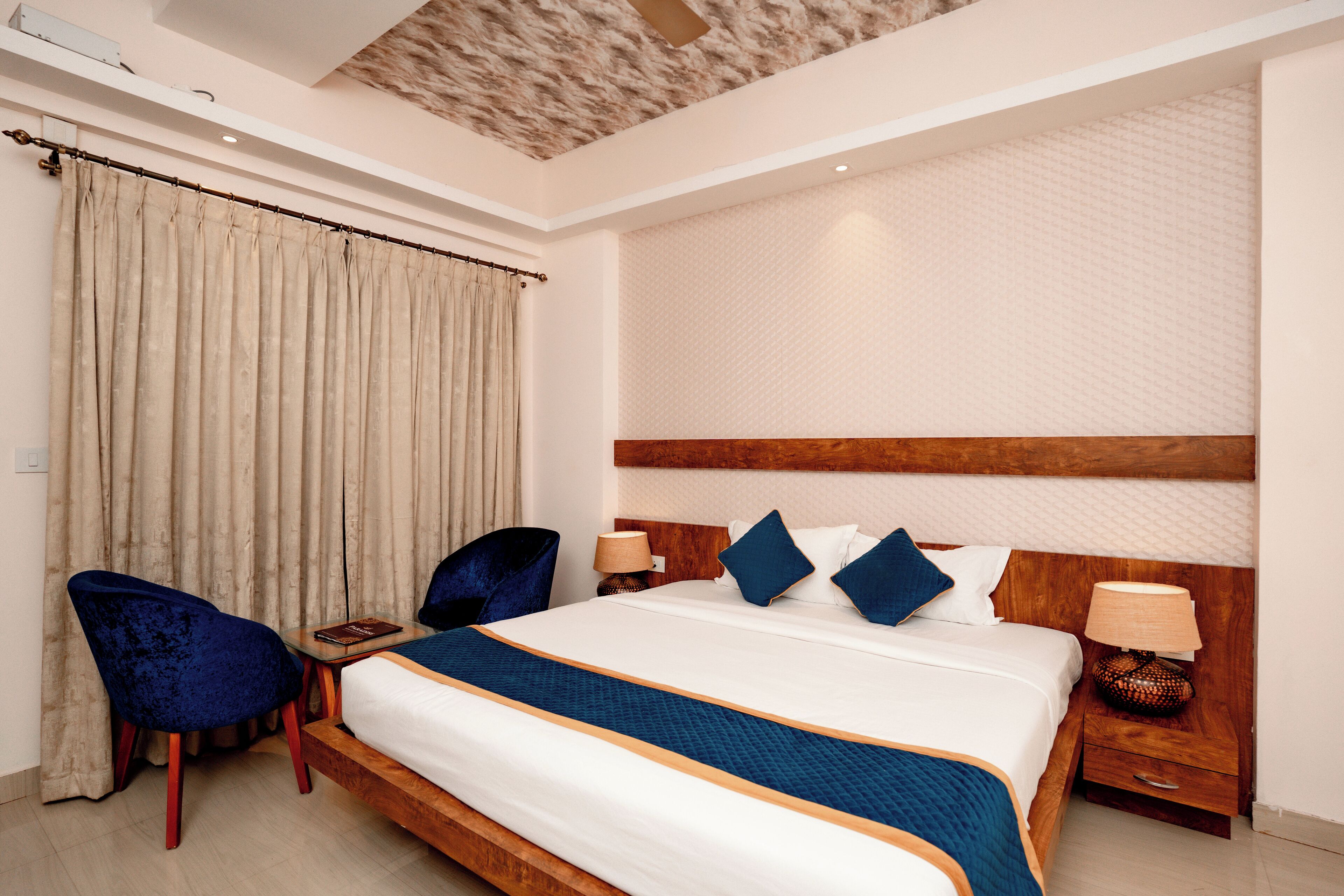 A hotel room with a large bed, two bedside tables, a chair, and a curtain.