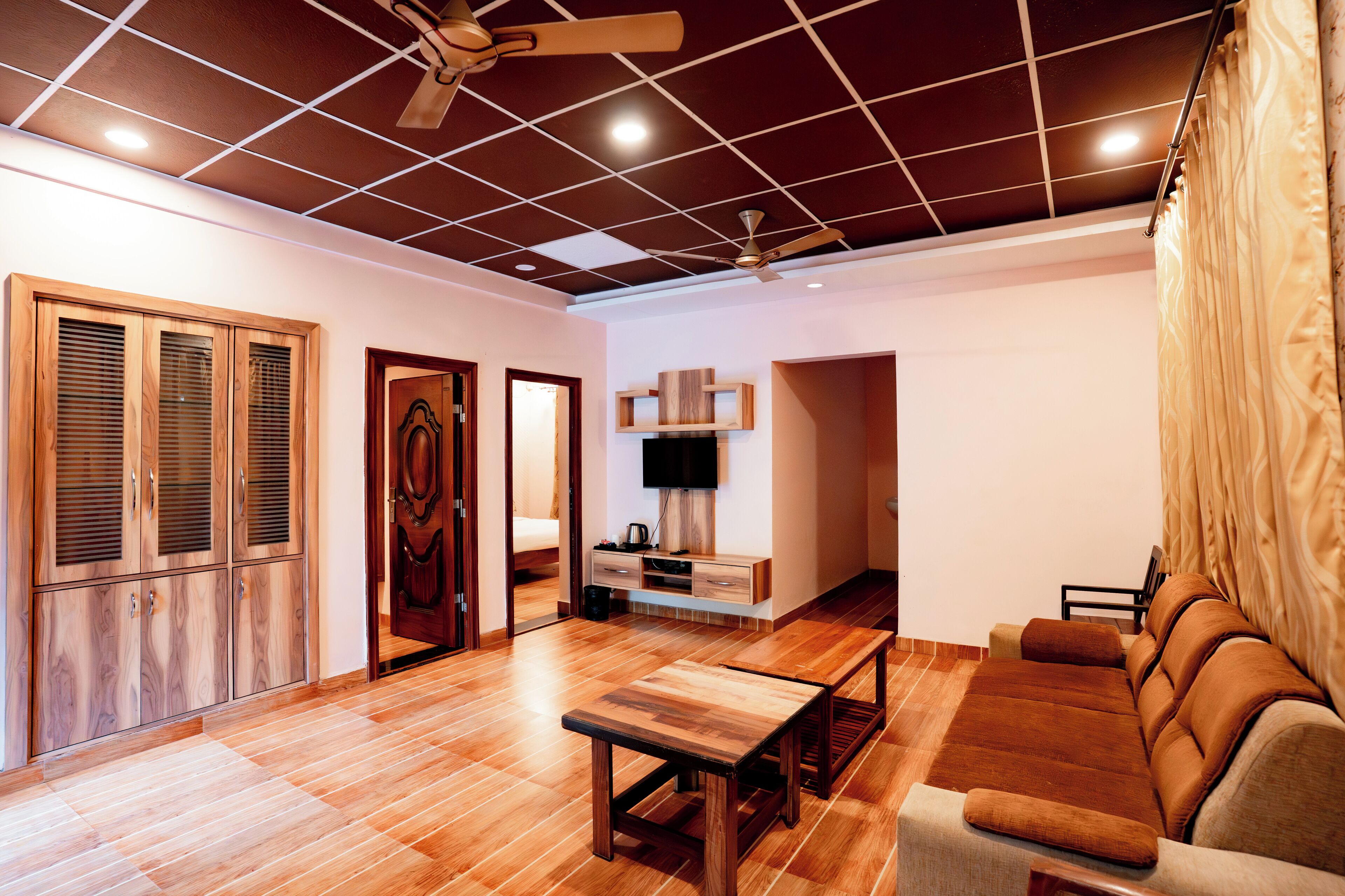 A modern living room with wooden flooring, a sofa, a coffee table, and a ceiling fan.
