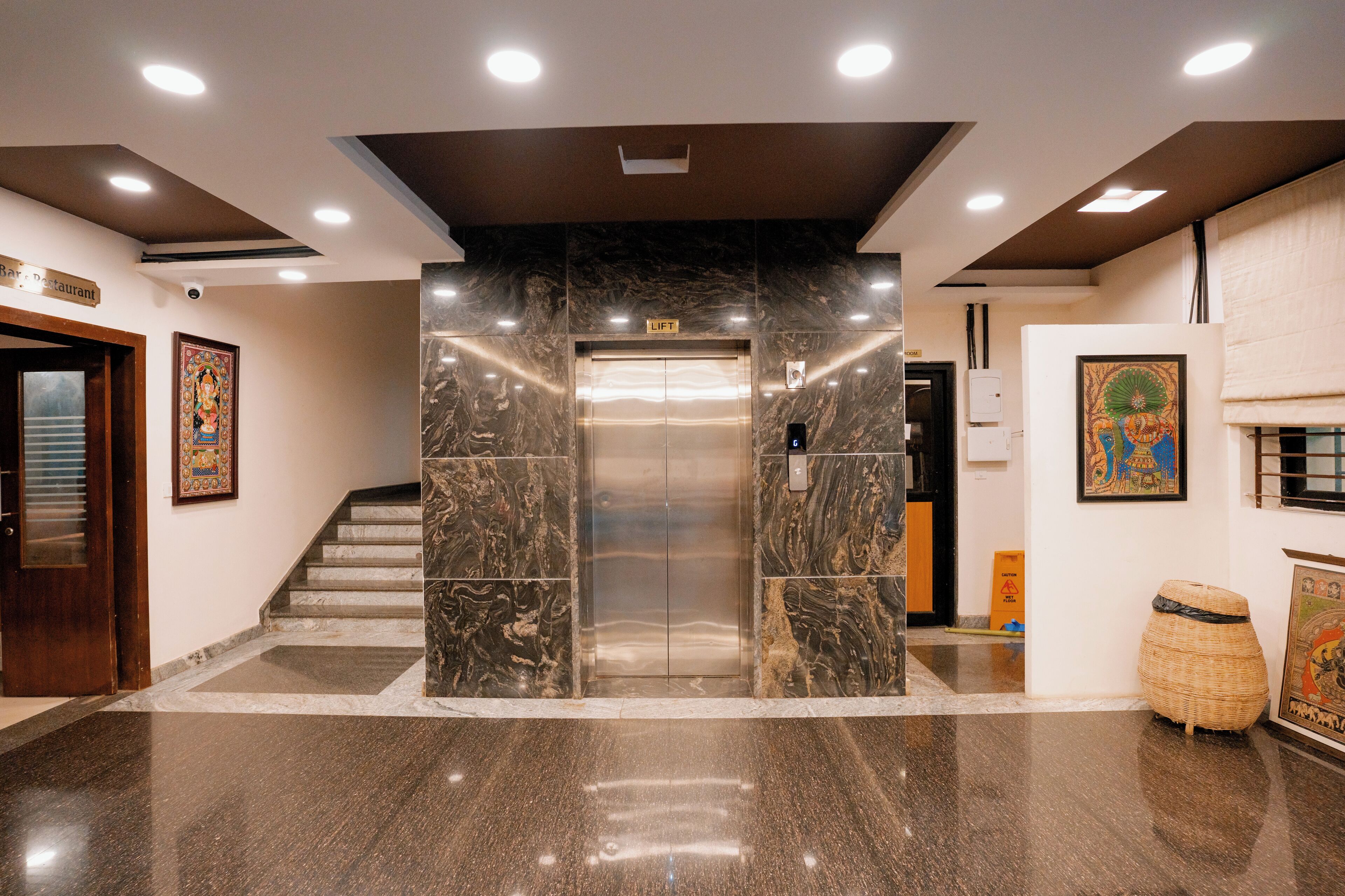 An elevator in a lobby with marble walls and a polished floor.