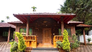 A wooden cabin with a tiled roof, a wooden front door, and a porch with steps leading to it.