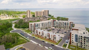 A modern apartment complex with multiple buildings, parking areas, and a waterfront view. - Waterfront 20Ppl Townhouse Hot tub Sauna (Hamilton)