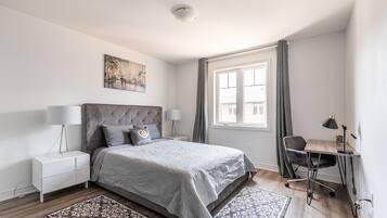 Une chambre moderne avec un grand lit, un bureau et une fenêtre avec des rideaux.