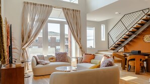 Un salon spacieux comprenant deux canapés, une table basse et un escalier menant à l’étage supérieur.