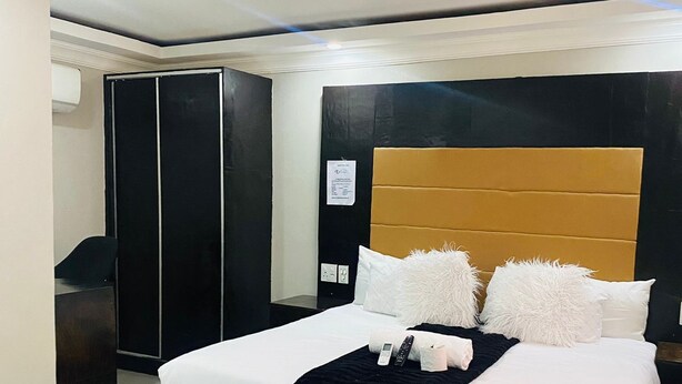 A modern hotel room with a large bed, a desk, and a wardrobe. - DBright Guest Lodge (Pretoria)