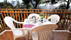 Ein Balkon mit einem Tisch für zwei Personen, ausgestattet mit einem Wasserkocher, Tassen und einem Buch.