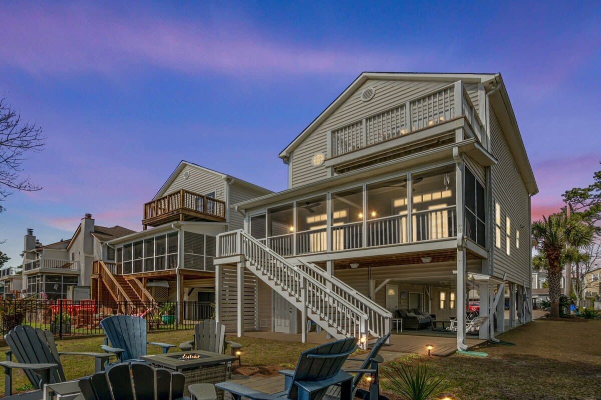 A two-story house with a covered porch, outdoor seating area, and a staircase leading to the upper level.