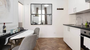 Una cocina compacta con comedor, un espejo grande y una estufa moderna.