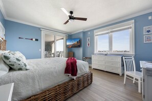 A bedroom with a bed, a ceiling fan, a window, and a view of the outside.