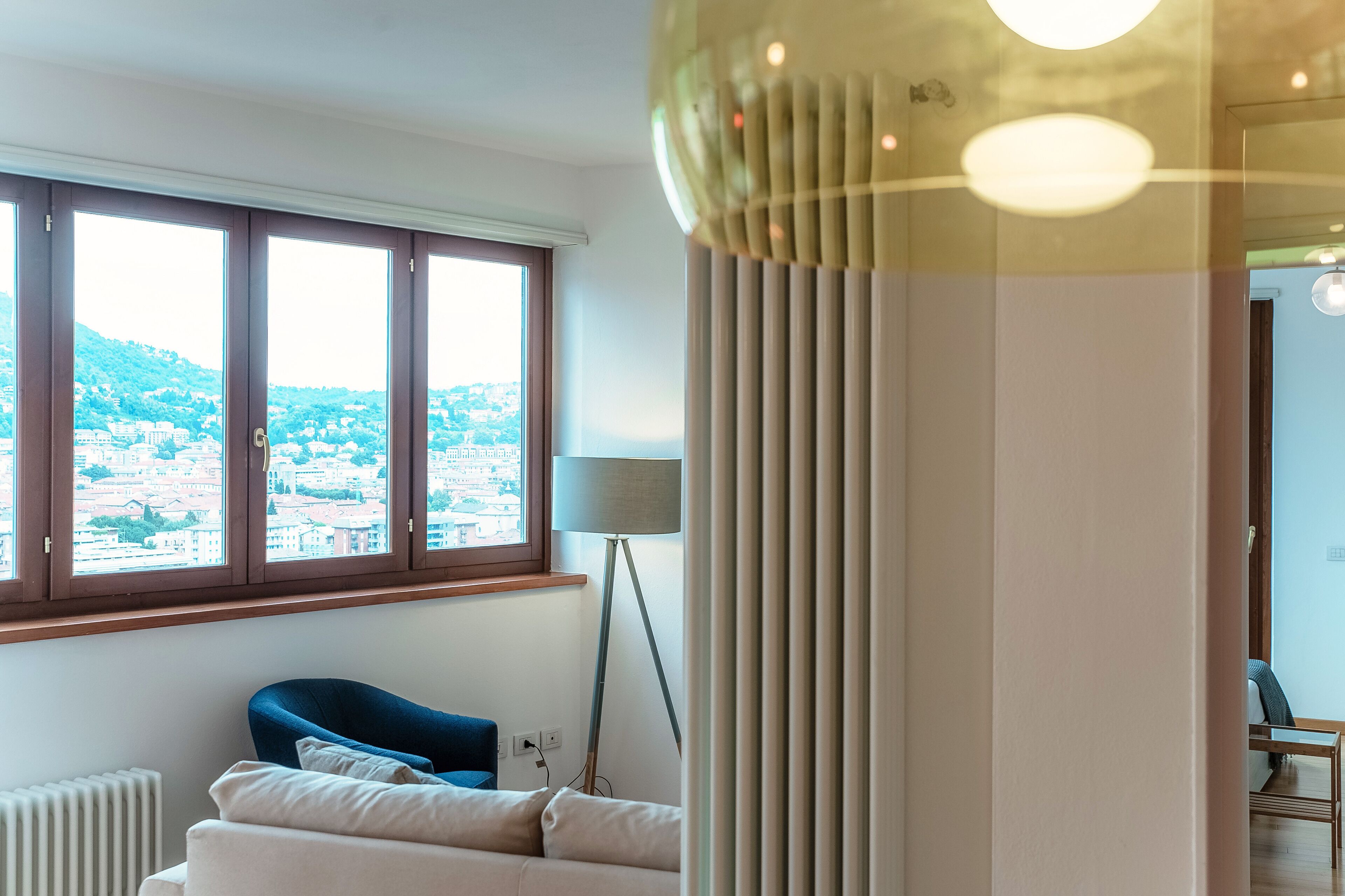 Une chambre d’hôtel moderne avec une grande fenêtre, un lampadaire et une vue sur le paysage urbain.