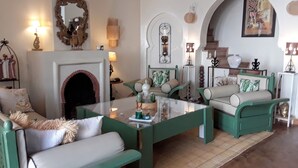 Een knus woongedeelte met groene meubels, een open haard en decoratieve wandkunst.