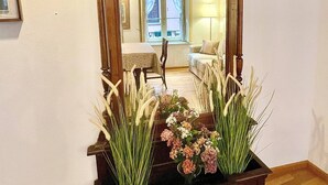 A mirror with a wooden frame, a floral arrangement in front, and a framed picture on the wall. - Nest In Como - A Nest In The City Of Como for 6 (Como)