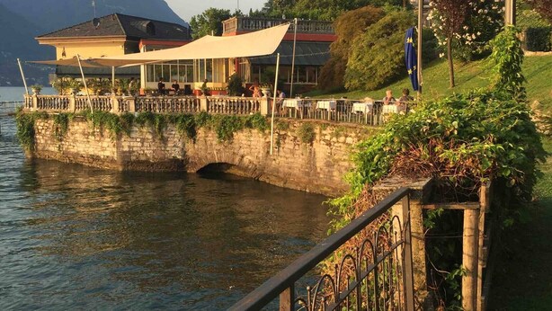 A lakeside restaurant with outdoor seating, a stone wall, and a view of the lake and mountains. - Nest In Como - A Nest In The City Of Como for 6 (Como)