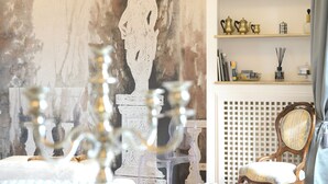 Ein Zimmer mit einer weißen Statue, einem hölzernen Stuhl und Regalen mit Dekoration.
