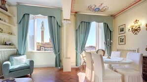 Ein Zimmer mit Blick auf einen Turm, einem Esstisch mit Stühlen und einem Sofa.