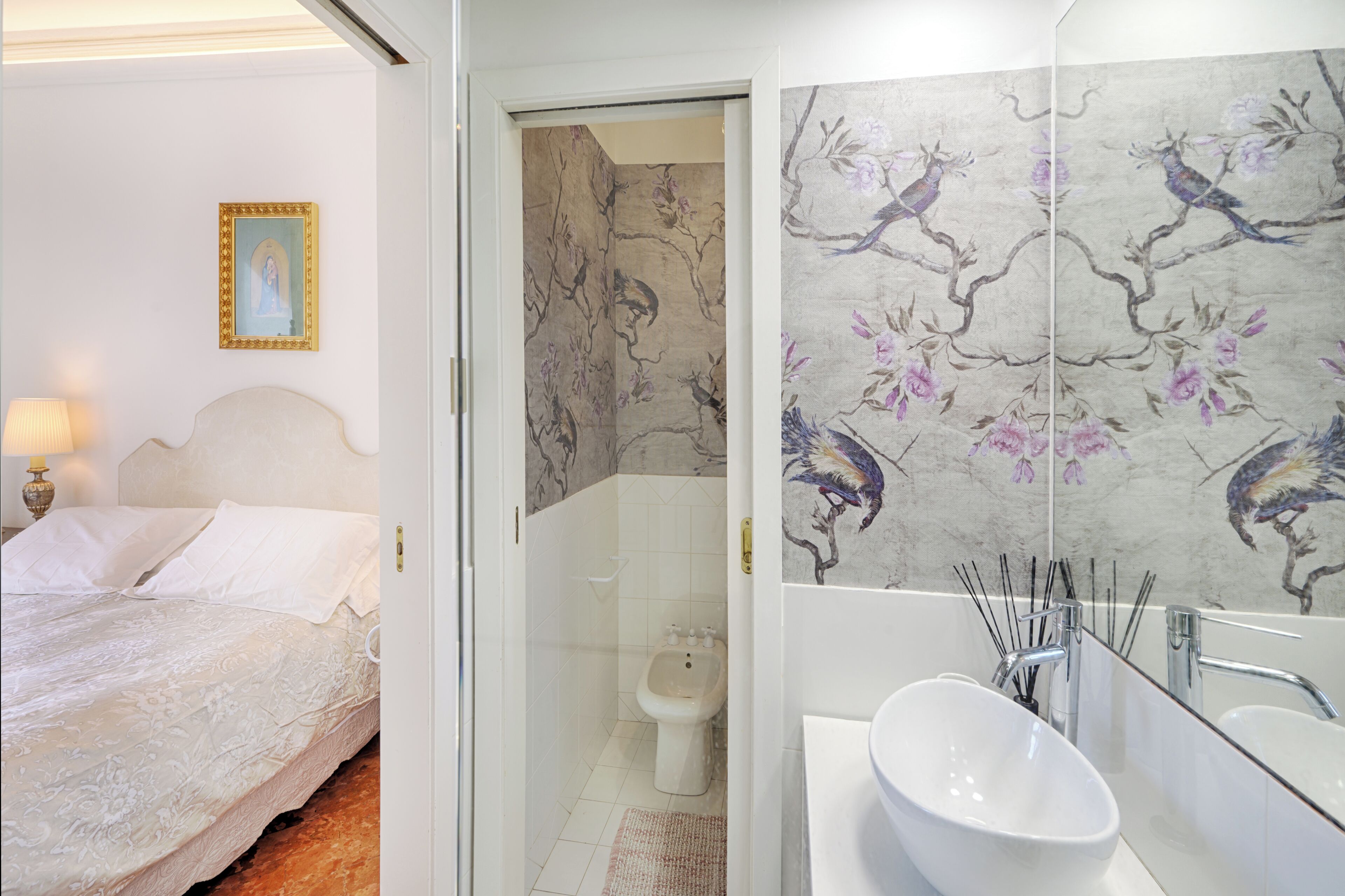 A hotel room with a bed, a bathroom with a sink and mirror, and a toilet.