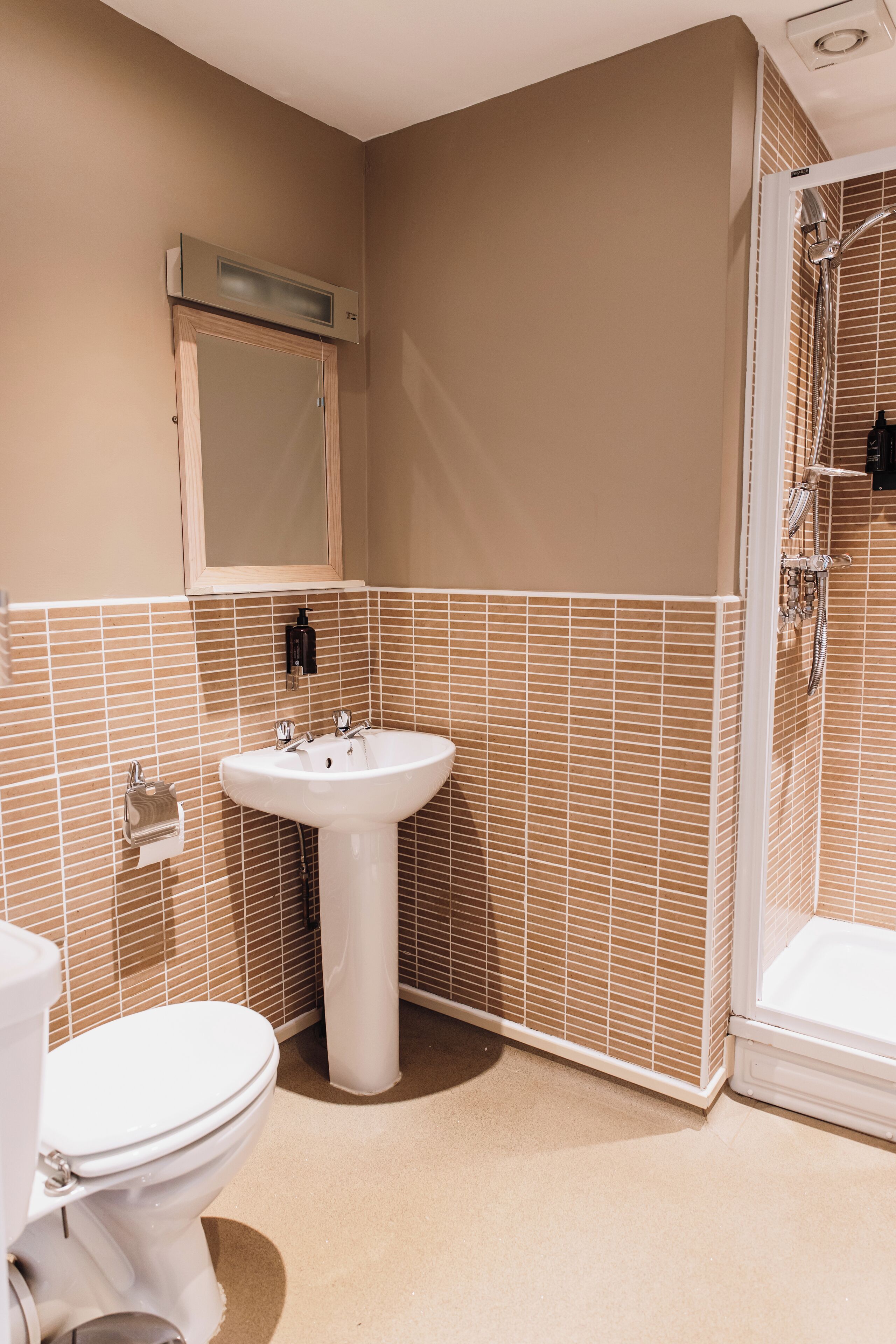 Un baño con lavamanos, inodoro y ducha blancos.