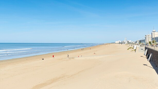 A wide sandy beach with a clear blue sky, a few people, and buildings in the background. - Cozy 2-BR House with Terrace, Near Forest and Beaches, Sleeps 6 (Saint-Jean-de-Monts)