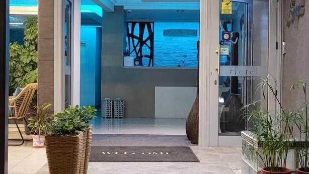 A modern hotel entrance with a welcoming mat, potted plants, and a view into the interior. - HOTEL AKROPOL (Katerini)