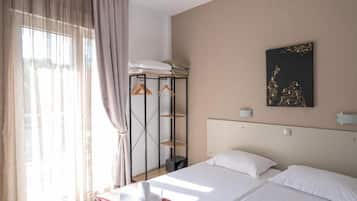 Ein Hotelzimmer mit Bett, Kleiderschrank, einem Bild an der Wand und einem Fenster mit Vorhängen.