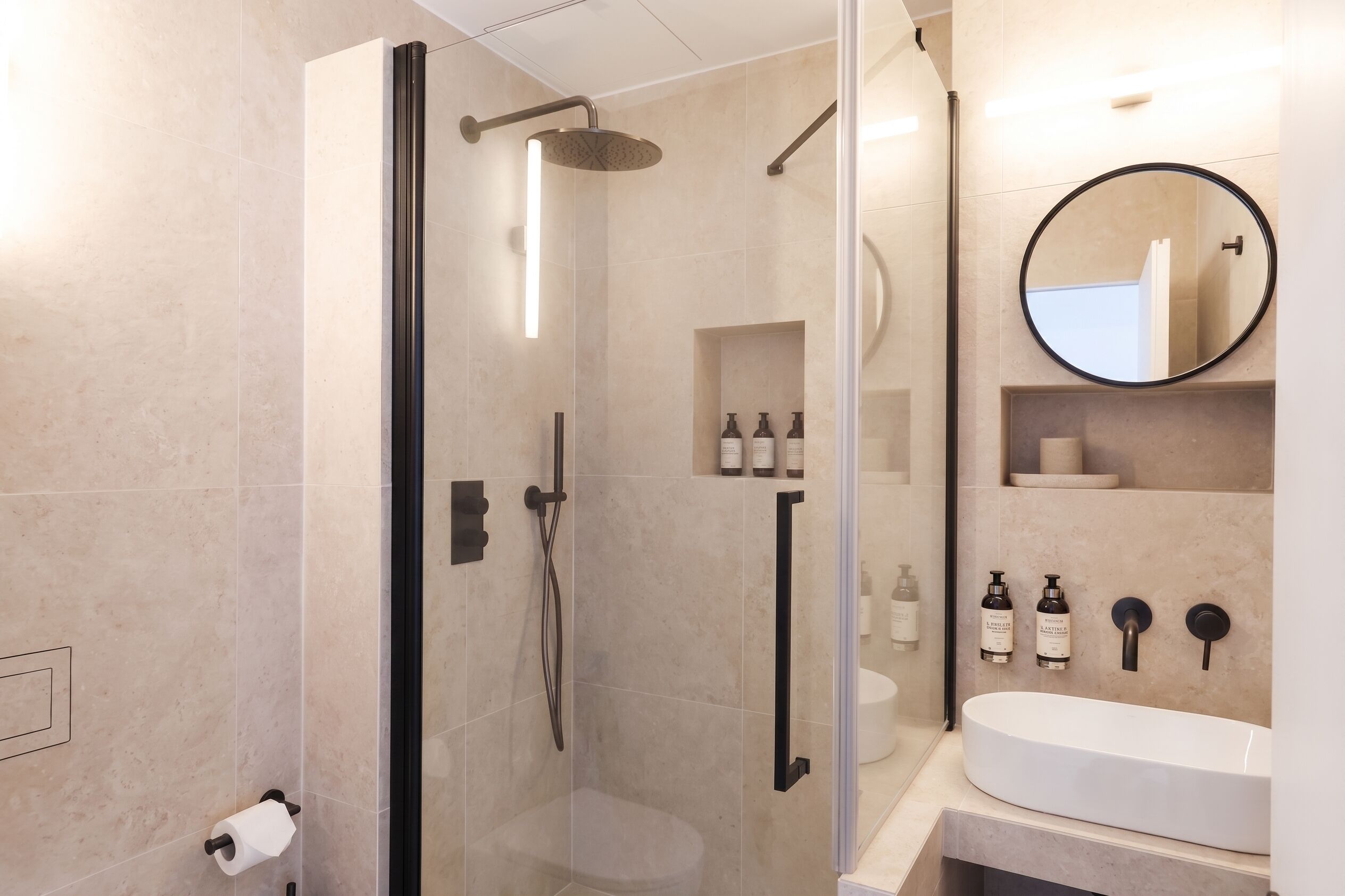 Ein modernes Badezimmer mit einer Duschkabine aus Glas, einem weißen Waschbecken und einem Spiegel.
