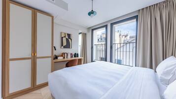 Una habitación de hotel con cama, escritorio, armario y vistas a la ciudad.