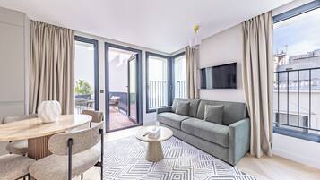 A modern living room with a sofa, a round coffee table, and a dining area with chairs and a table.