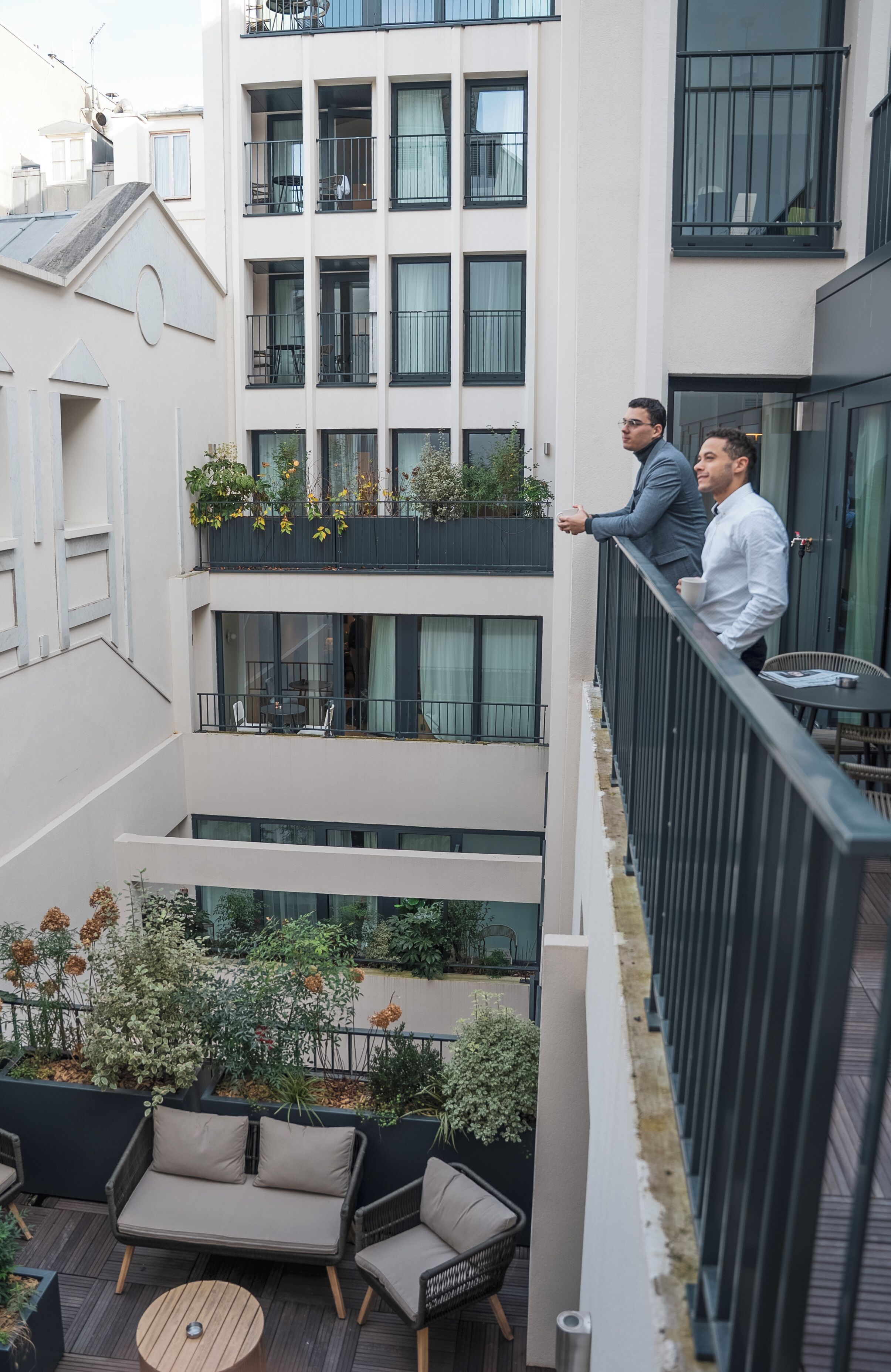 Un edificio de varios pisos con balcones, mobiliario exterior y plantas.