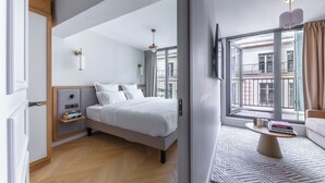 A modern hotel room with a large bed, bedside tables, a view of the city through large windows, and a balcony. - Aparthotel Quartier Libre Opéra (Paris)