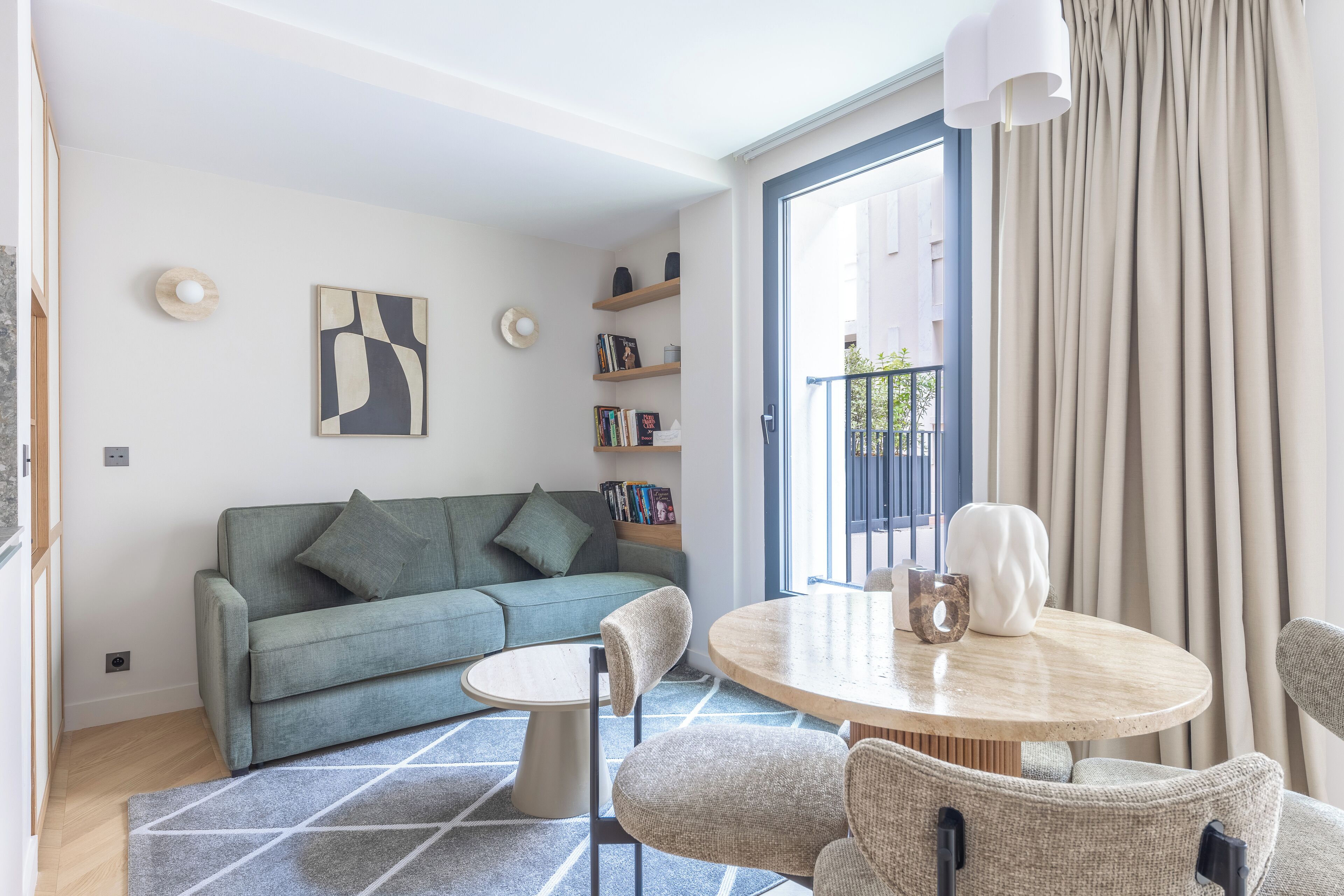 A modern living room with a sofa, a round table, and a bookshelf.