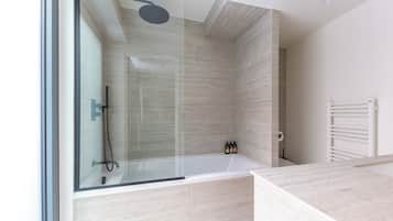 A modern bathroom with a glass-enclosed shower, a white bathtub, and a built-in toilet.